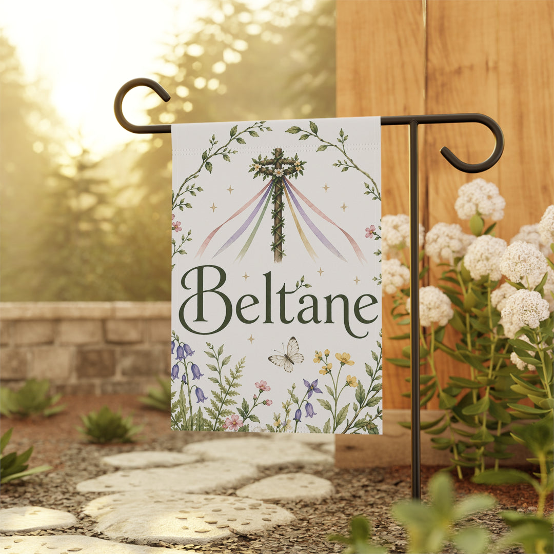 Decorative garden flag with 'Beltane' text and floral design on a stand outdoors.