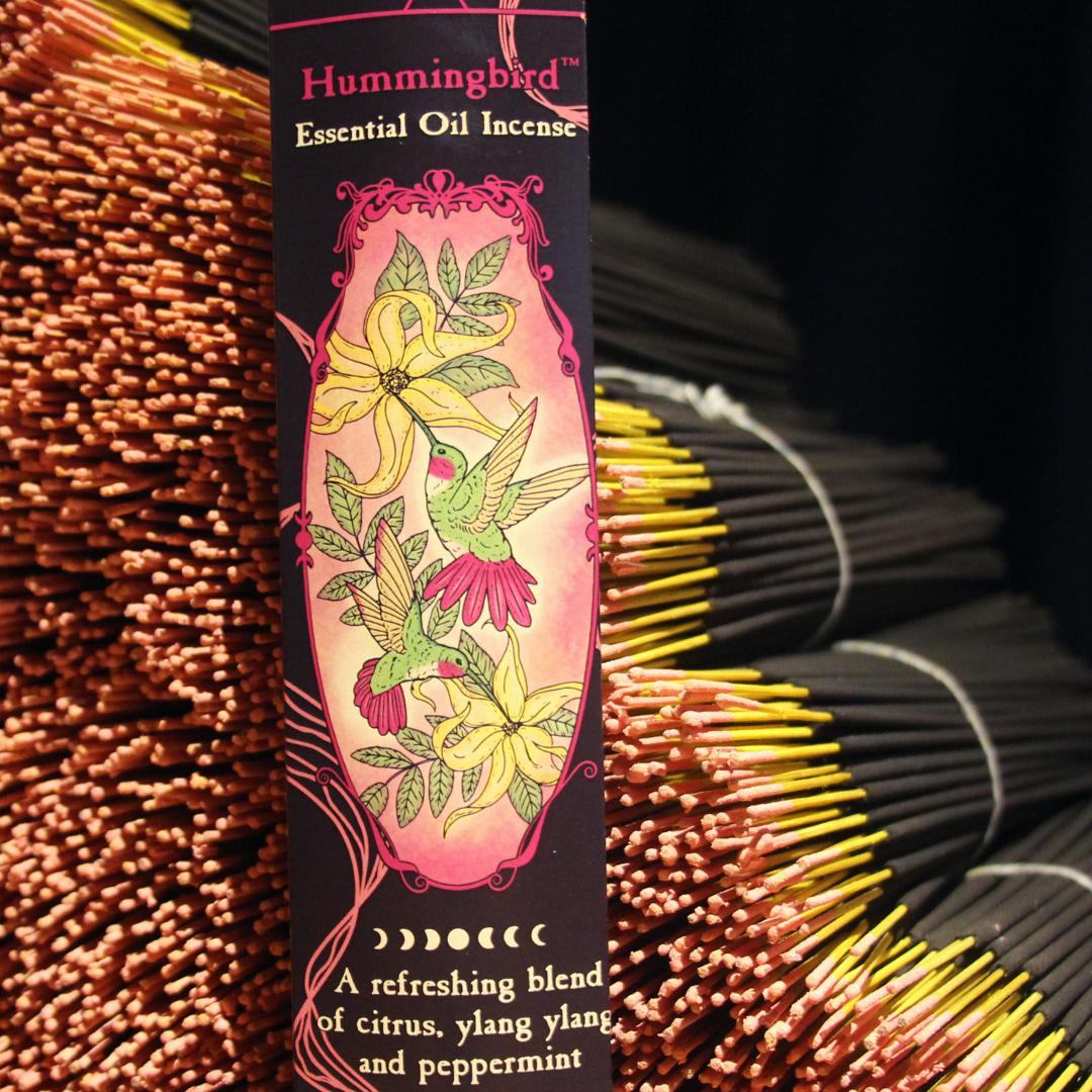 Hummingbird Premium Incense box with pink floral hummingbird artwork, surrounded by incense sticks.