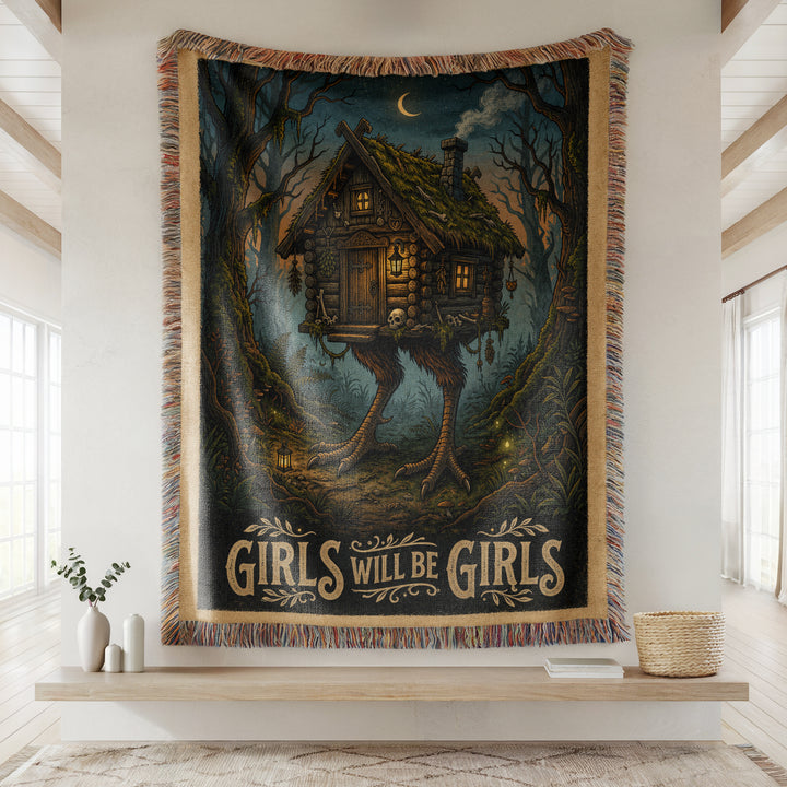 Tapestry with a Baba Yaga Hut cabin design and 'Girls Will Be Girls' text in a room setting.