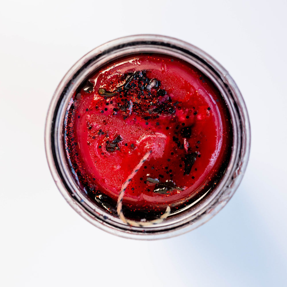 Close-up of a red candle in a glass jar with a white background