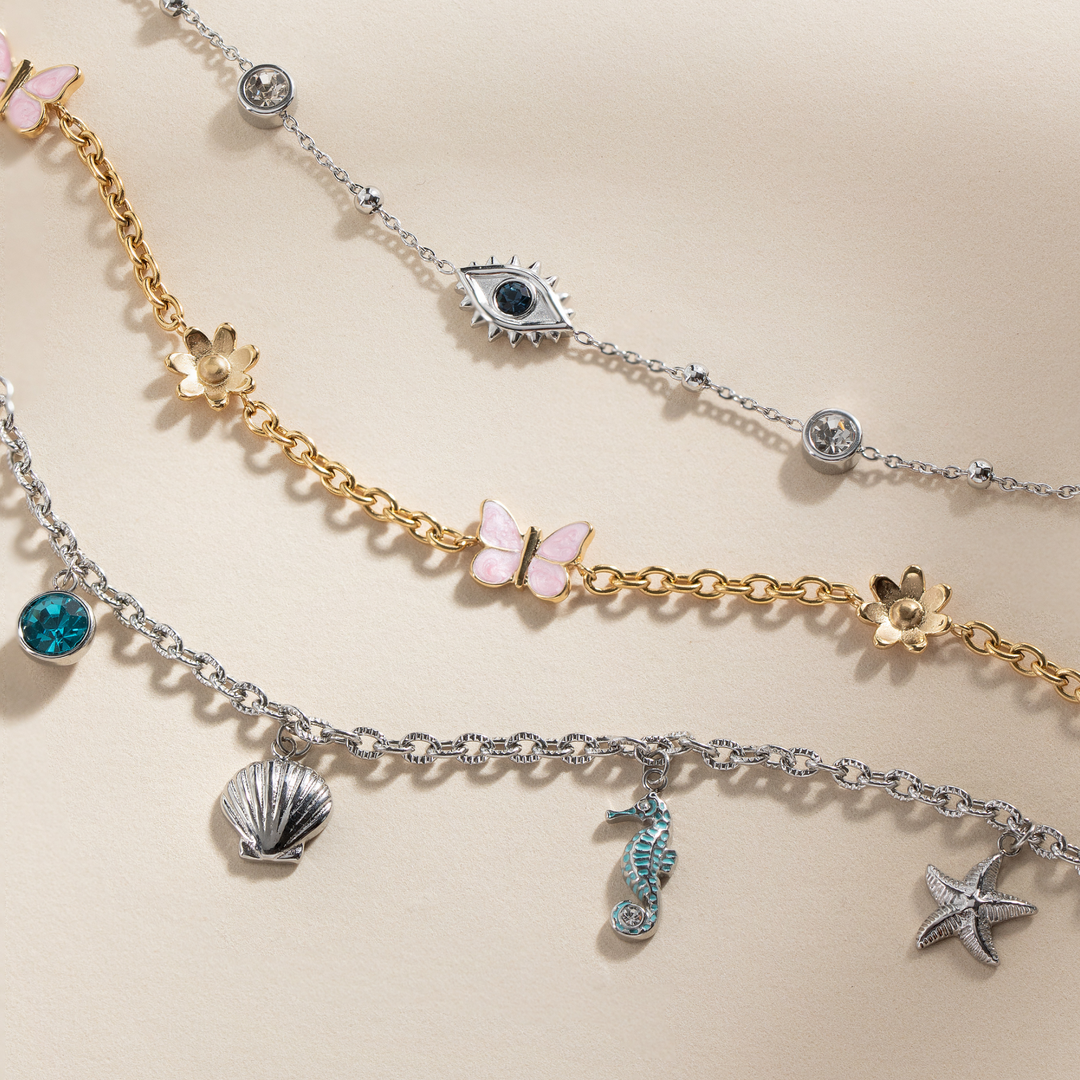 Two layered charm bracelets with various charms on a beige background