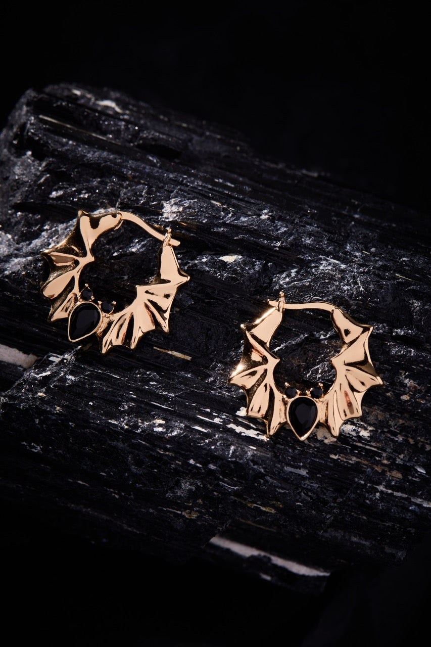 Gold hoop earrings on a dark stone surface