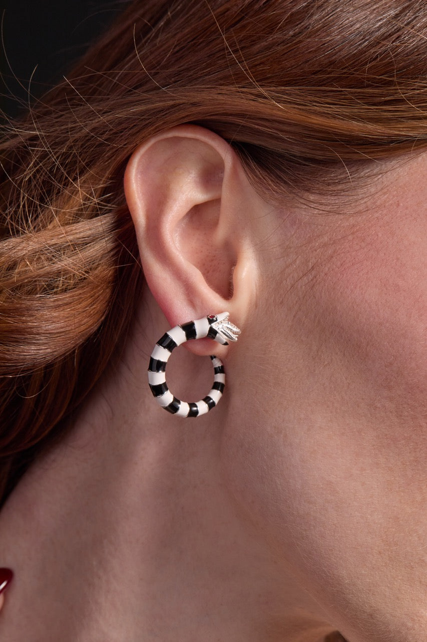 Close-up of an ear wearing a black and white hoop earring with a blurred background.