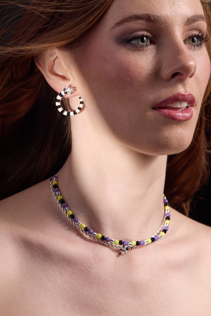 Close-up of a woman wearing a colorful beaded necklace and hoop earrings.