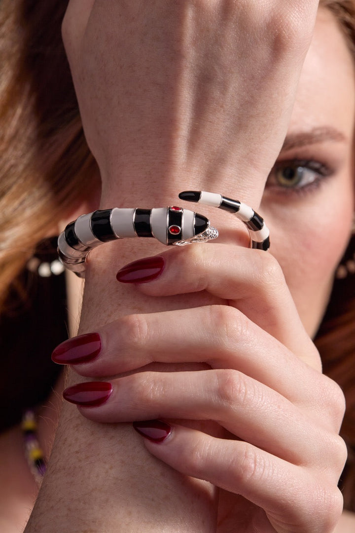 Close-up of a hand wearing a black and white striped ring with a red gemstone.