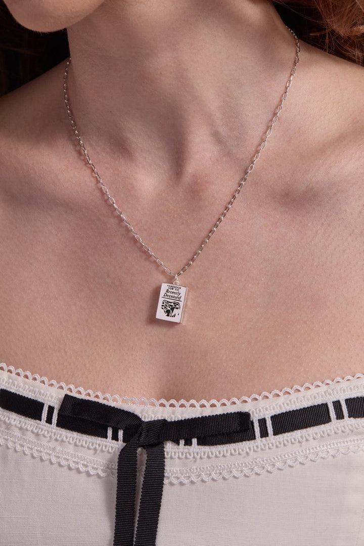 Handbook for the Recently Deceased Necklace with a pendant worn by a person, focusing on the necklace and skin.