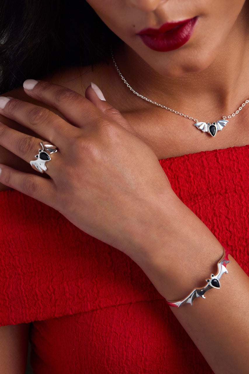 Close-up of a person wearing silver jewelry with black stones on a red background