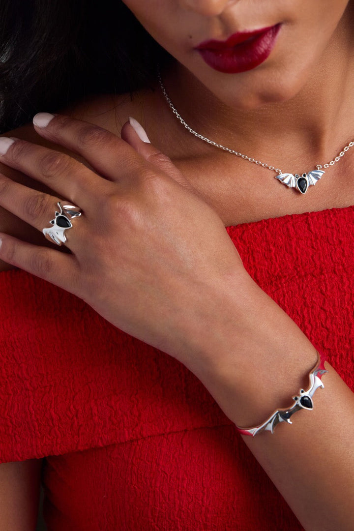 Close-up of a person wearing silver jewelry with black stones on a red background