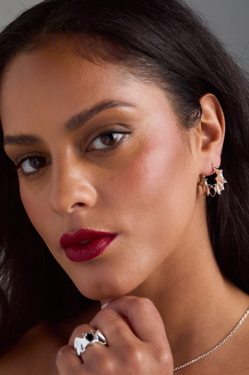 Close-up of a woman wearing earrings and a ring with a dark background