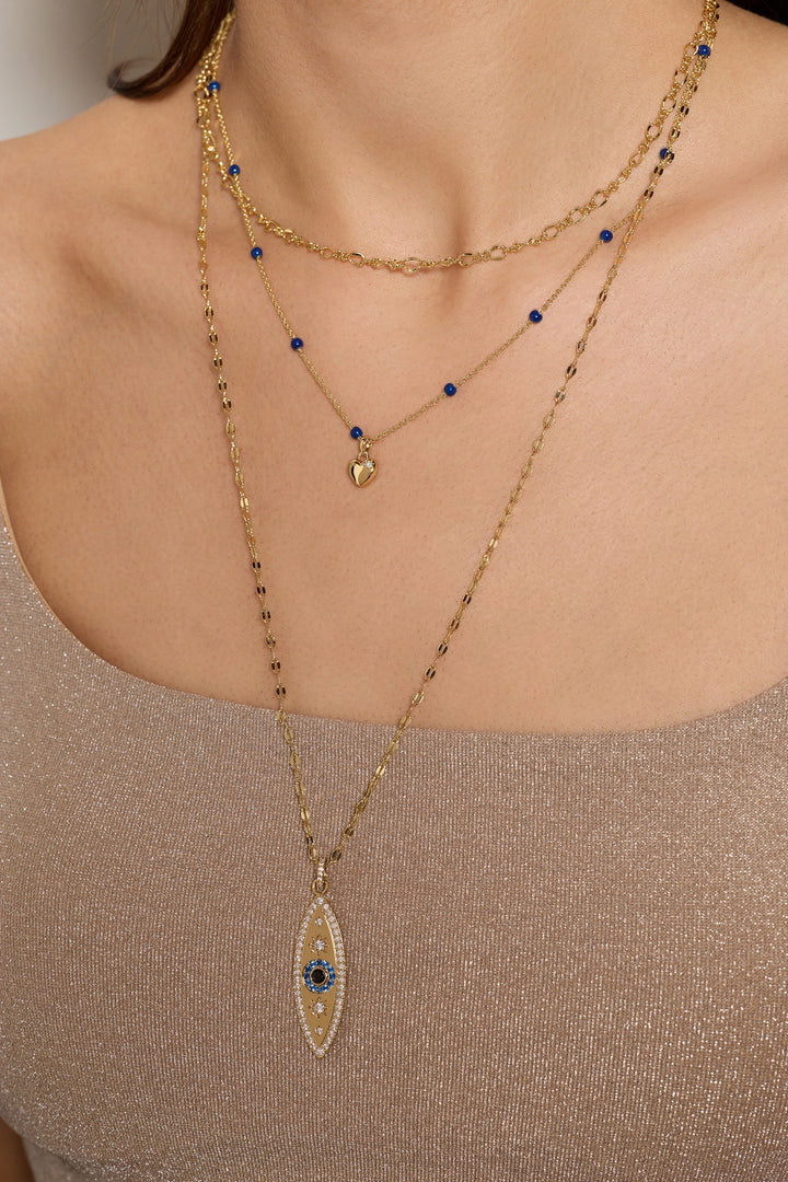 Necklace with an eye-shaped pendant worn by a person against a neutral background