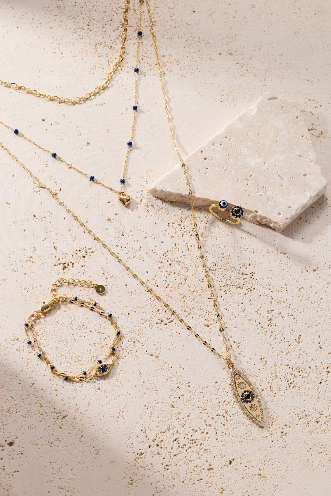 Gold jewelry set with necklaces and bracelets on a textured surface