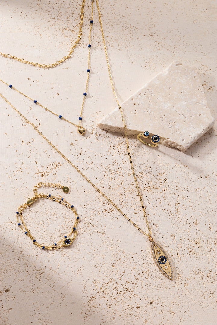 Gold jewelry set with necklaces and bracelets on a textured surface