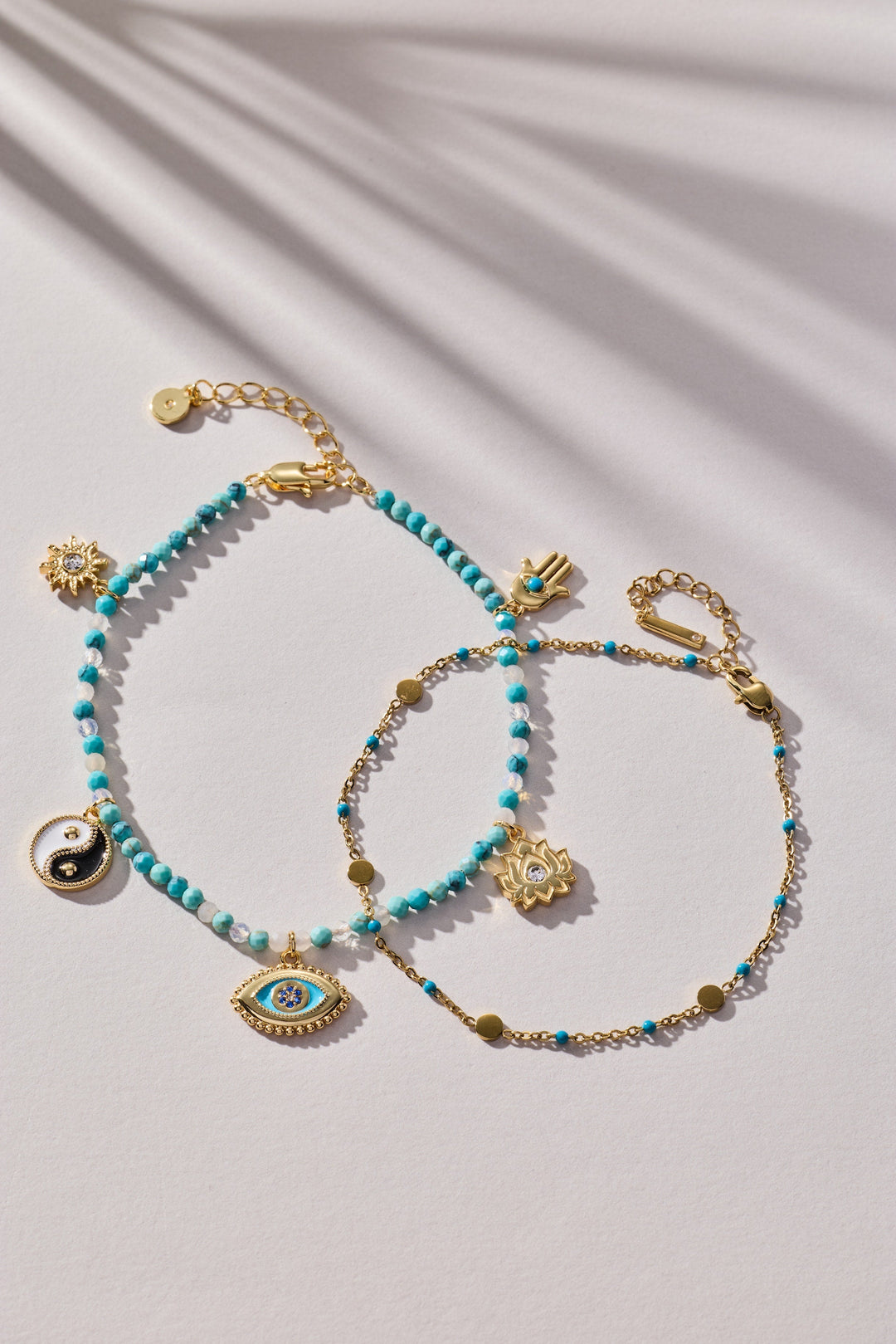 Turquoise beaded bracelet with gold accents and charms on a light background