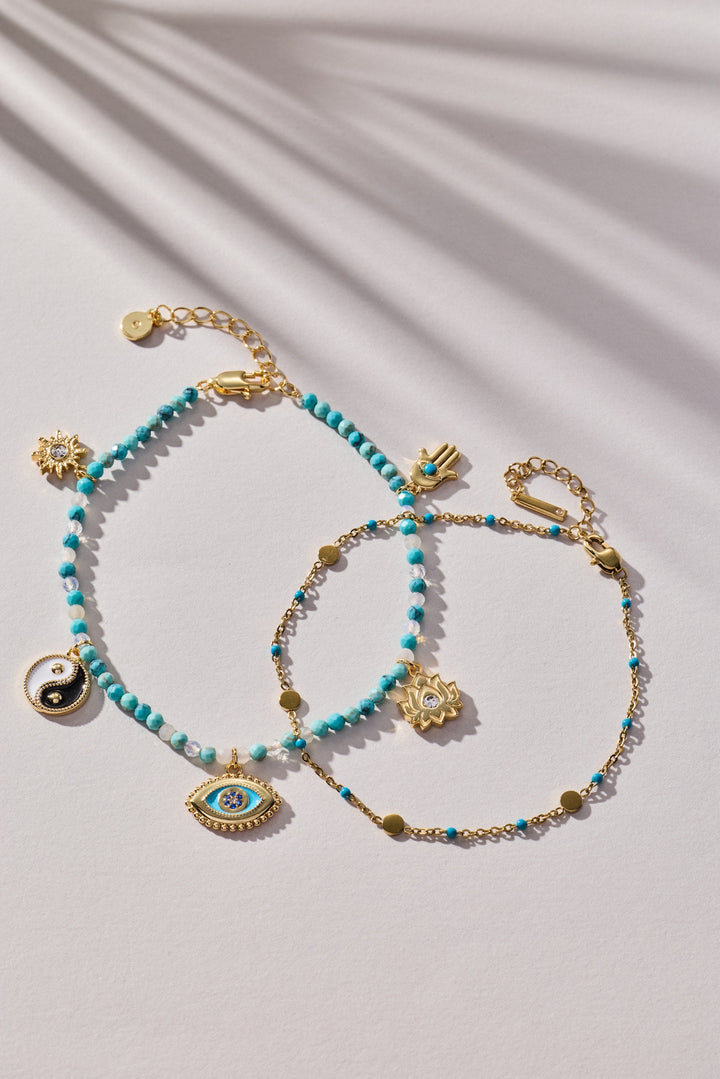 Turquoise beaded bracelet with gold accents and charms on a light background