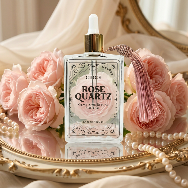 Circe Rose Quartz body oil bottle with pink roses and pearls on a decorative tray