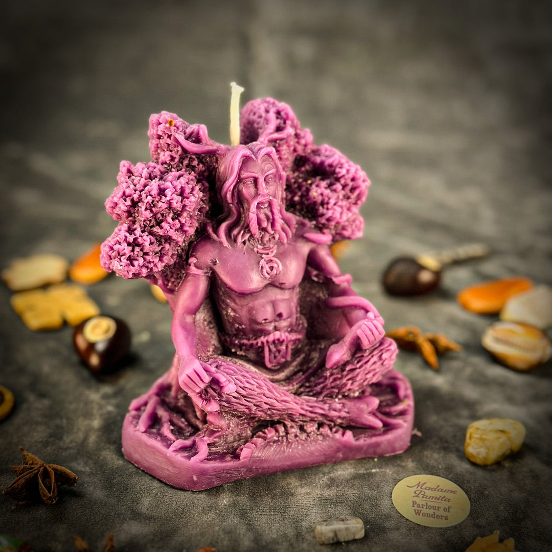 Beeswax Horned God Spell Candle with pink carved figure, lit wick, textured petals.