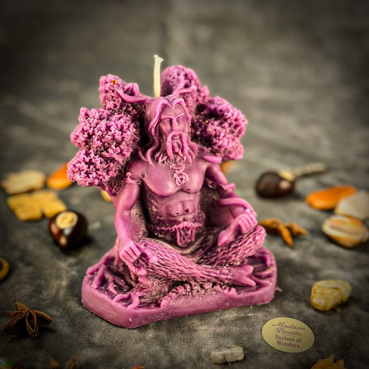 Beeswax Horned God Spell Candle with pink carved figure, lit wick, textured petals.