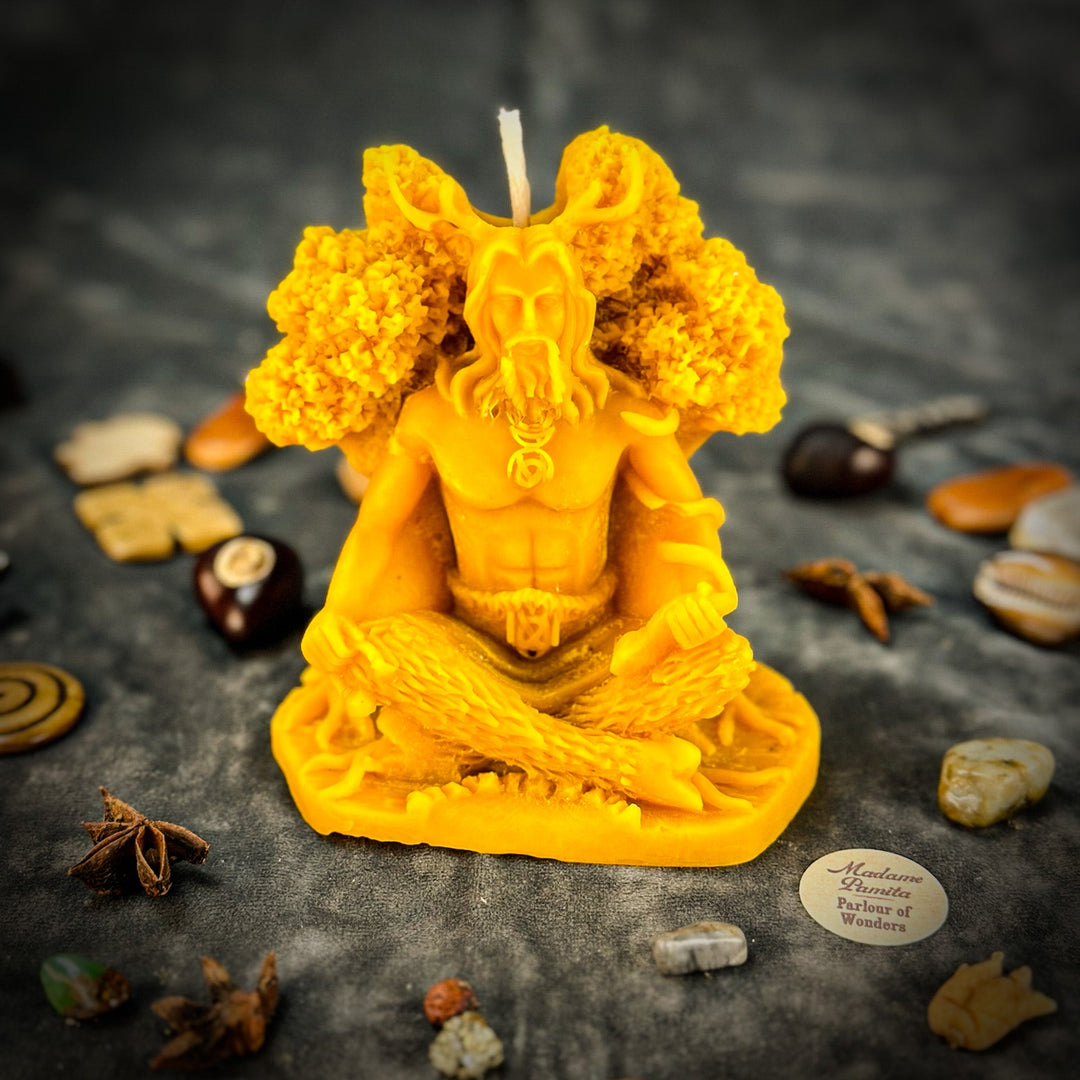 Beeswax Horned God Spell Candle with bright yellow flames, rocky background stones.