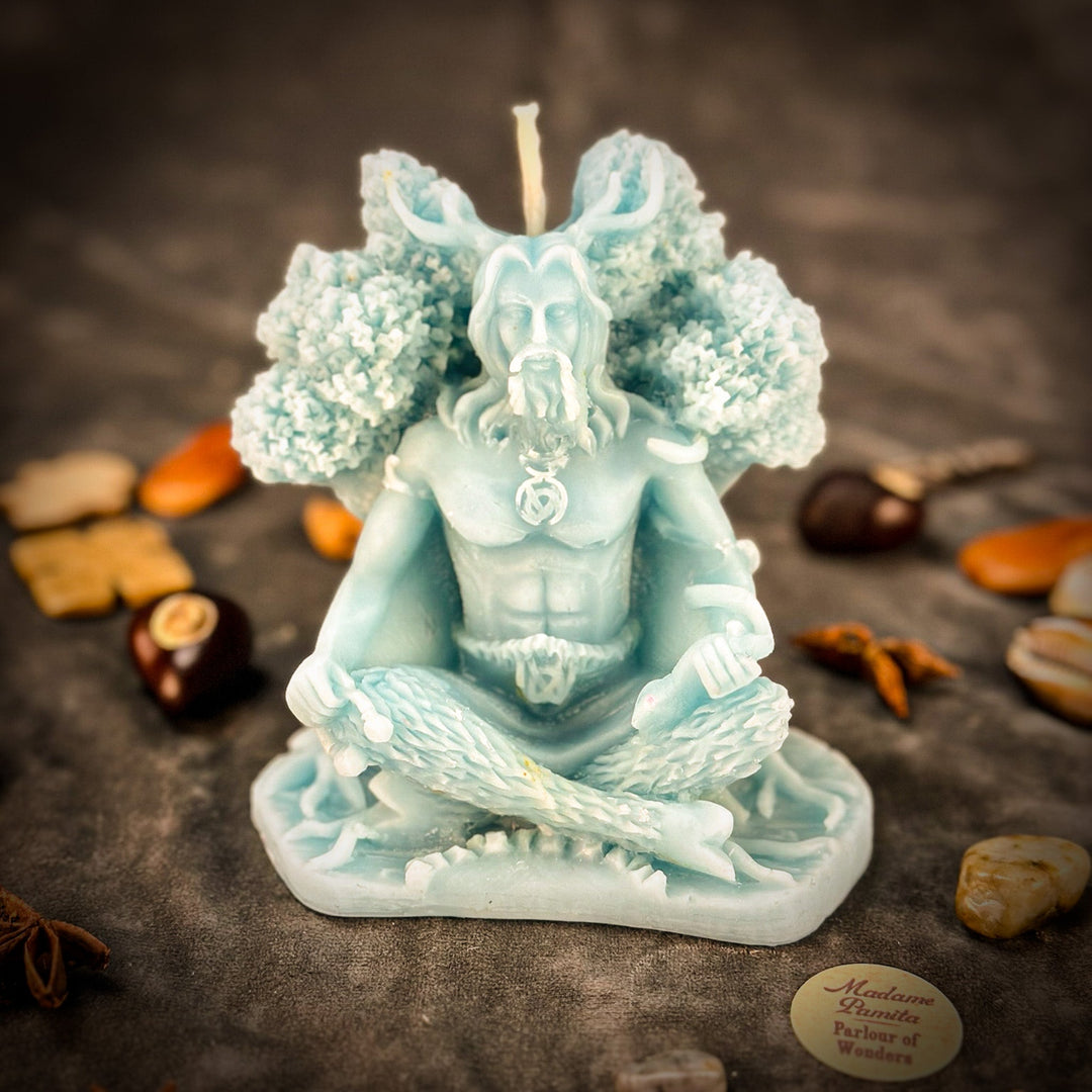 Beeswax Horned God Spell Candle with teal wings, raised flame, and hands holding charm.