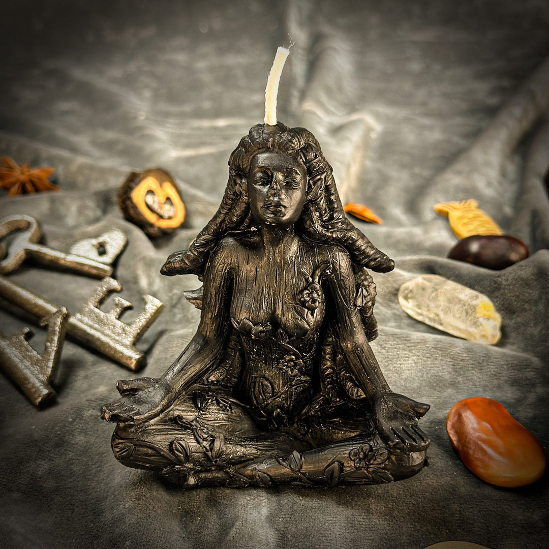 Beeswax Forest Fairy Spell Candle with lit wick atop dark bronze statue, scattered leaves.
