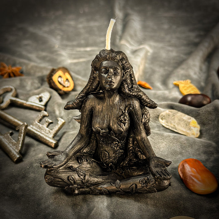 Beeswax Forest Fairy Spell Candle with lit wick atop dark bronze statue, scattered leaves.