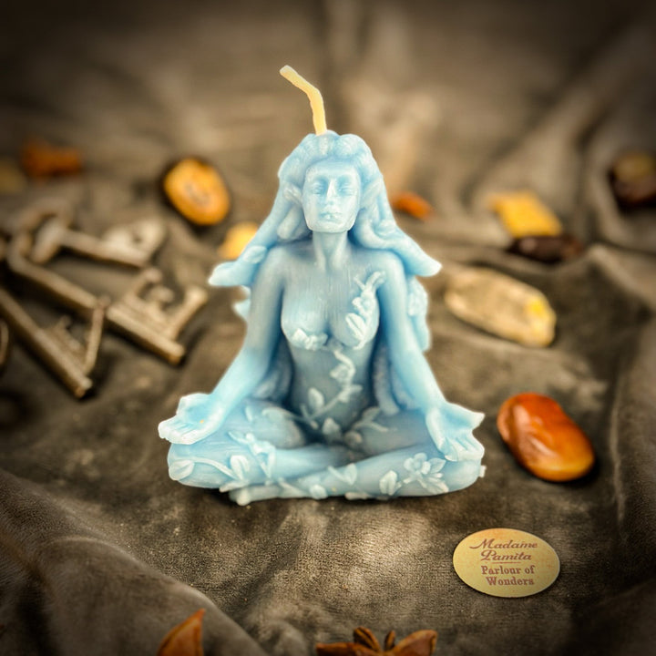 Beeswax Forest Fairy Spell Candle shaped like a light-blue figure, lit.