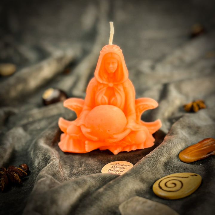 Beeswax Moon Goddess Spell Candle with orange carved figure, lit wick, close-up.