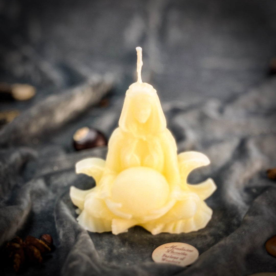 Beeswax Moon Goddess Spell Candle with glowing flame, close-up on gray stones.