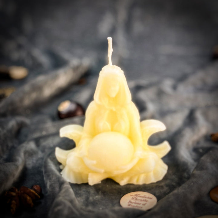 Beeswax Moon Goddess Spell Candle with glowing flame, close-up on gray stones.
