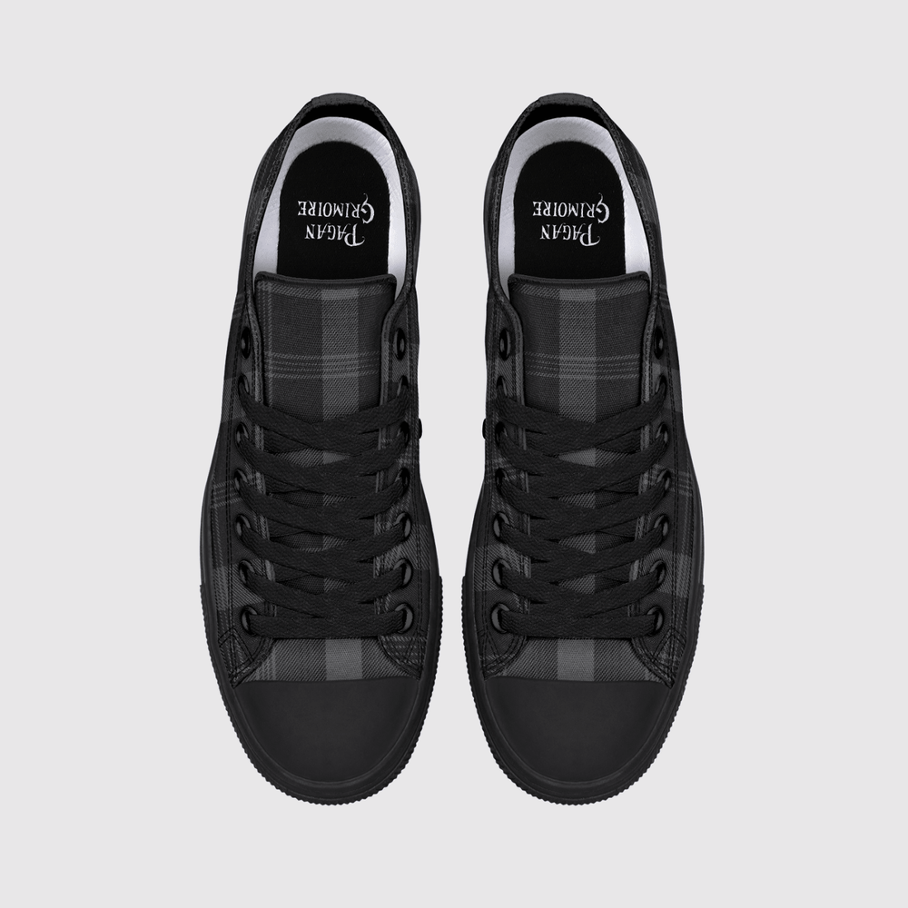 A pair of black low-top sneakers shown from a top-down view on a light gray background. The shoes feature black laces, a black rubber toe cap, and a black and gray plaid pattern on the side panels.