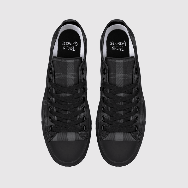 A pair of black low-top sneakers shown from a top-down view on a light gray background. The shoes feature black laces, a black rubber toe cap, and a black and gray plaid pattern on the side panels.