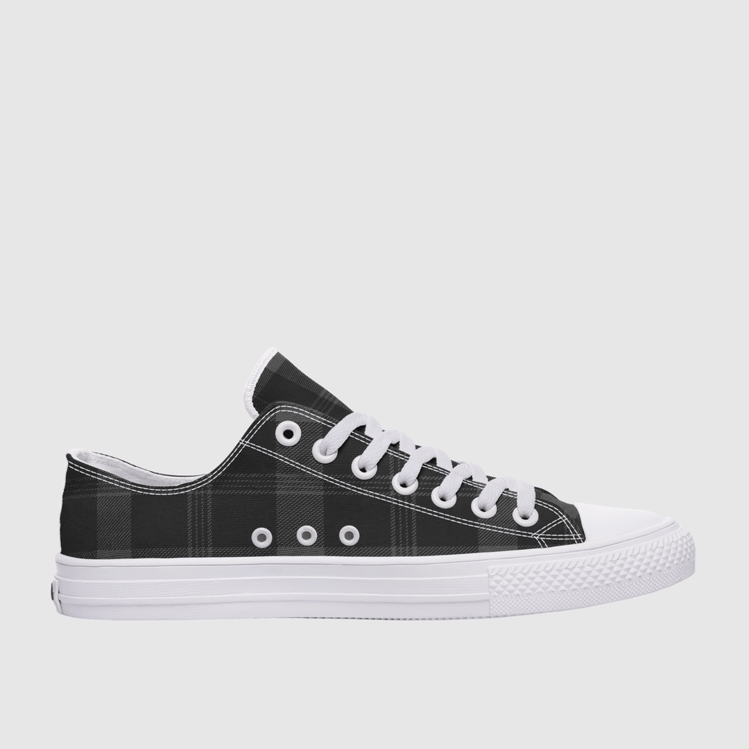 A low-top canvas sneaker with a black and gray plaid pattern on the upper, white laces, white eyelets, and a white rubber sole, shown from a side profile against a light gray background.