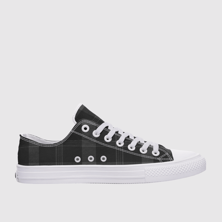 A low-top canvas sneaker with a black and gray plaid pattern on the upper, white laces, white eyelets, and a white rubber sole, shown from a side profile against a light gray background.