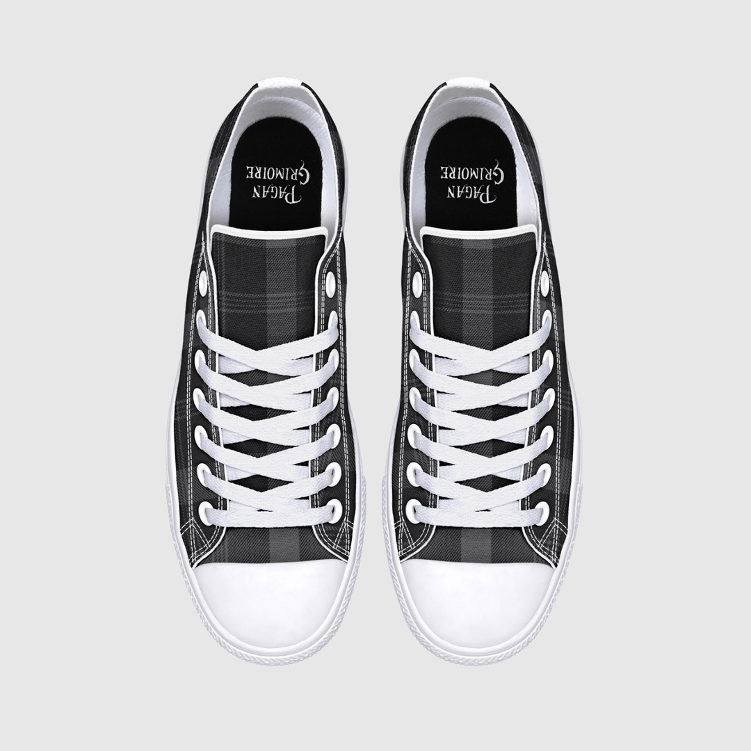 A pair of black and white plaid canvas low-top sneakers with white laces and white rubber toe caps, shown from a top-down view on a light gray background. 