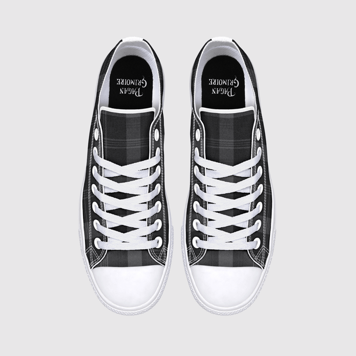 A pair of black and white plaid canvas low-top sneakers with white laces and white rubber toe caps, shown from a top-down view on a light gray background. 