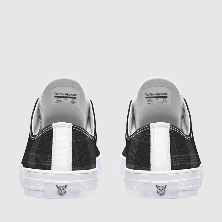 A pair of low-top slip-on sneakers shown from the back, featuring a black and white plaid pattern on the sides, a white vertical stripe, and a white rubber sole with a small owl head logo.