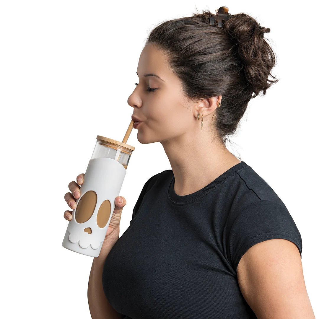 Woman drinking from a white tumbler with brown paw prints on a white background