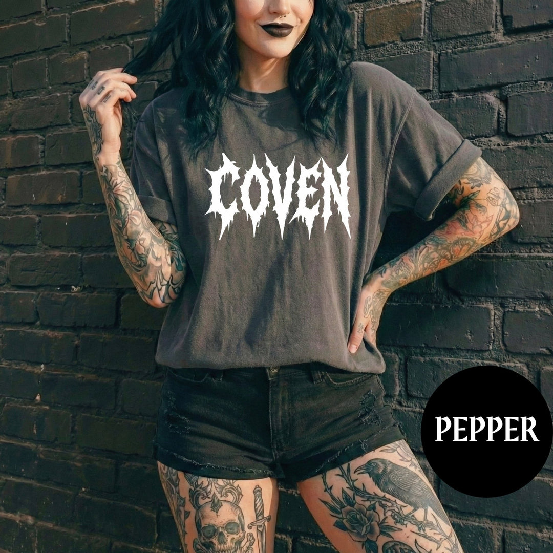 Person wearing a 'COVEN' t-shirt against a brick wall with 'PEPPER' branding.