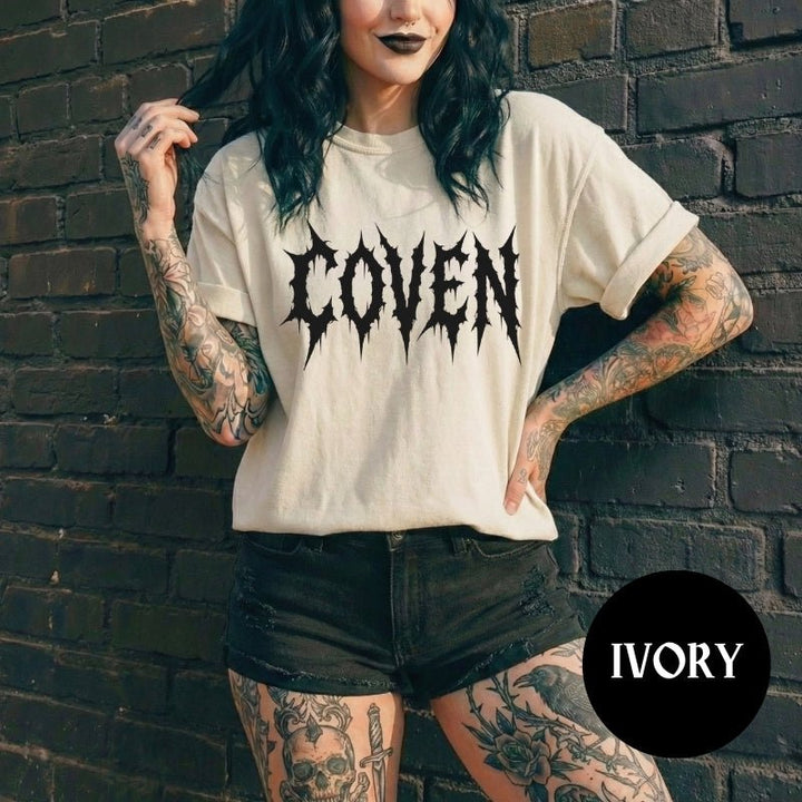 Person wearing a 'COVEN' t-shirt against a brick wall with 'IVORY' branding.
