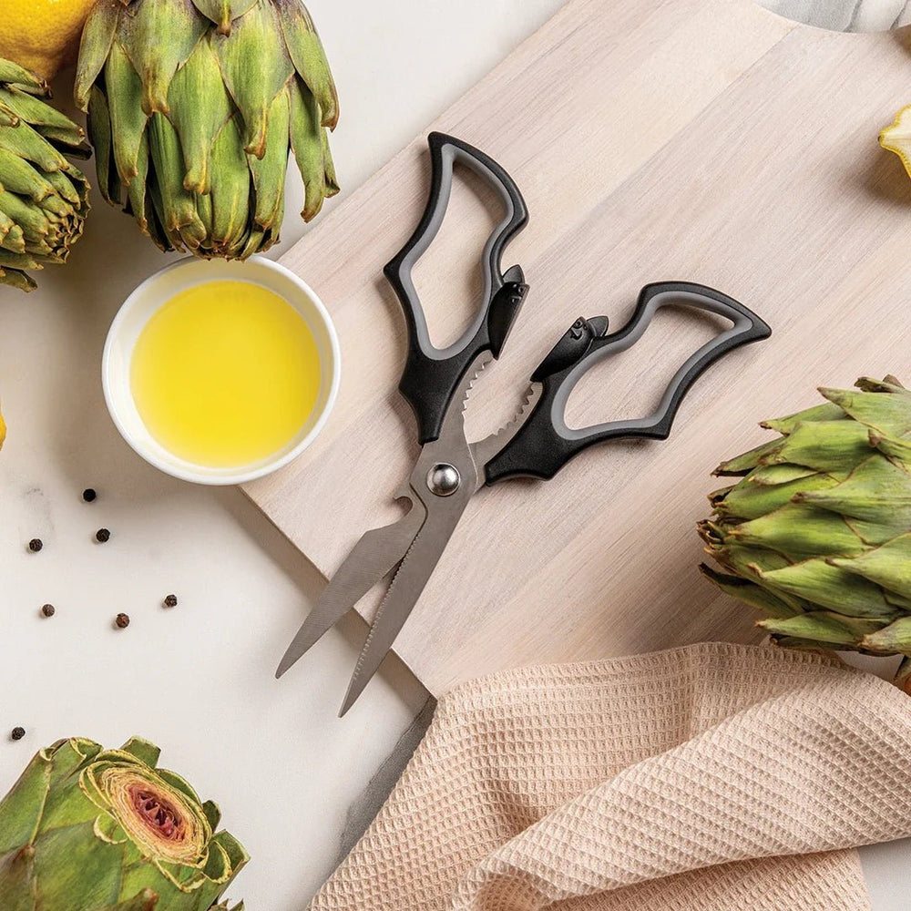 bat kitchen Shears, bowl of oil, and artichokes on a wooden surface