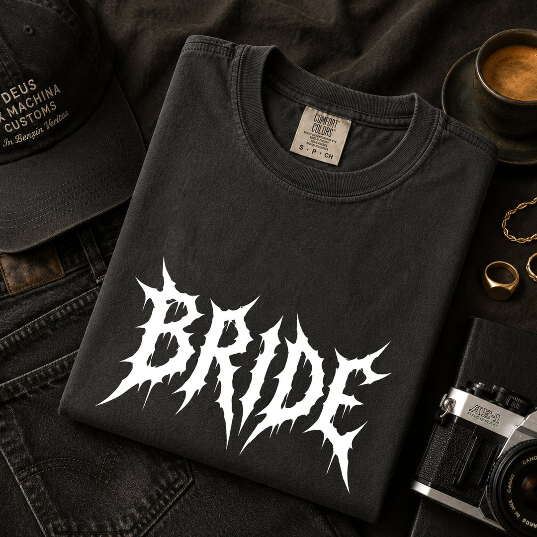 Black t-shirt with 'Bride' design on a dark surface with accessories.