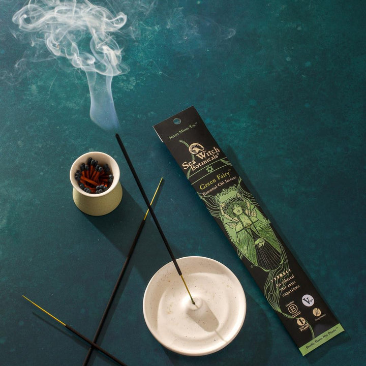 Incense Gift Set with green fairy box, black sticks, and smoldering smoke.