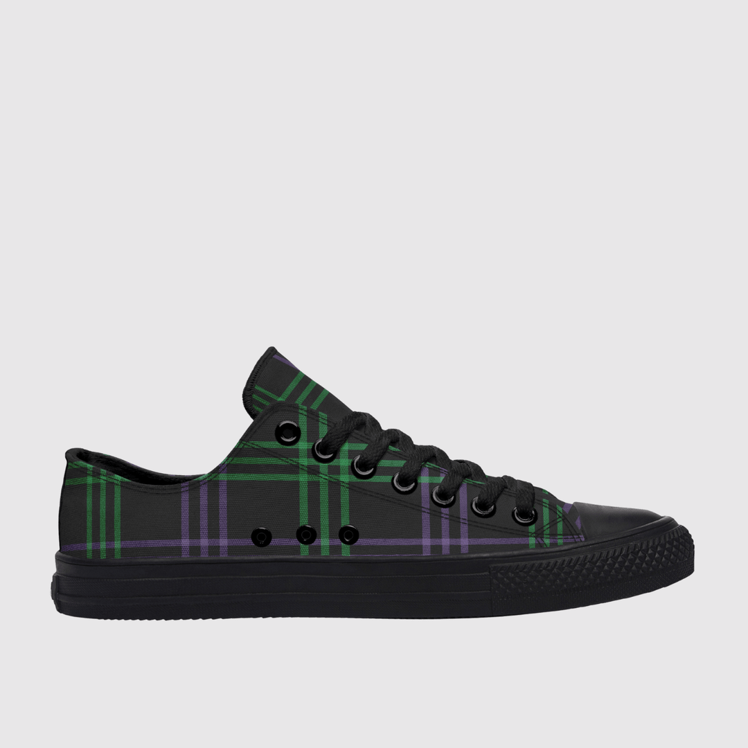 A low-top canvas sneaker in black with a green and purple tartan plaid pattern on the side panels, black laces, and a black rubber sole, shown against a light gray background.