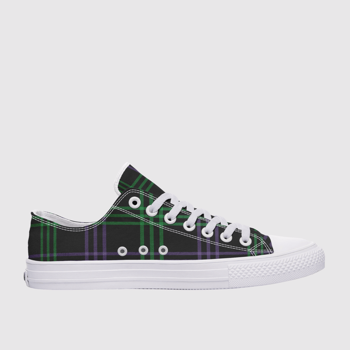 A low-top canvas sneaker featuring a green and purple tartan plaid pattern on the upper, white laces, white eyelets, and a white rubber sole, shown against a light gray background.