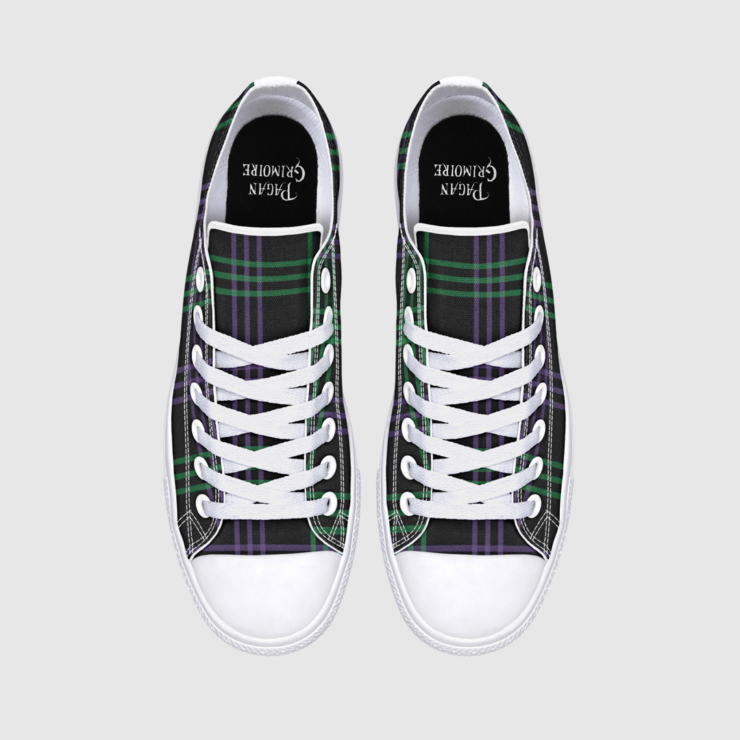 A pair of low-top canvas sneakers shown from a top-down view on a light gray background. The shoes feature a green and purple tartan plaid pattern on the sides, white laces, white rubber toe caps, and a black collar 