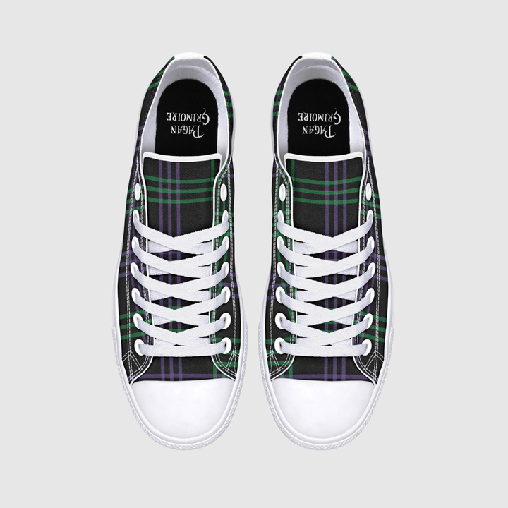 A pair of low-top canvas sneakers shown from a top-down view on a light gray background. The shoes feature a green and purple tartan plaid pattern on the sides, white laces, white rubber toe caps, and a black collar 