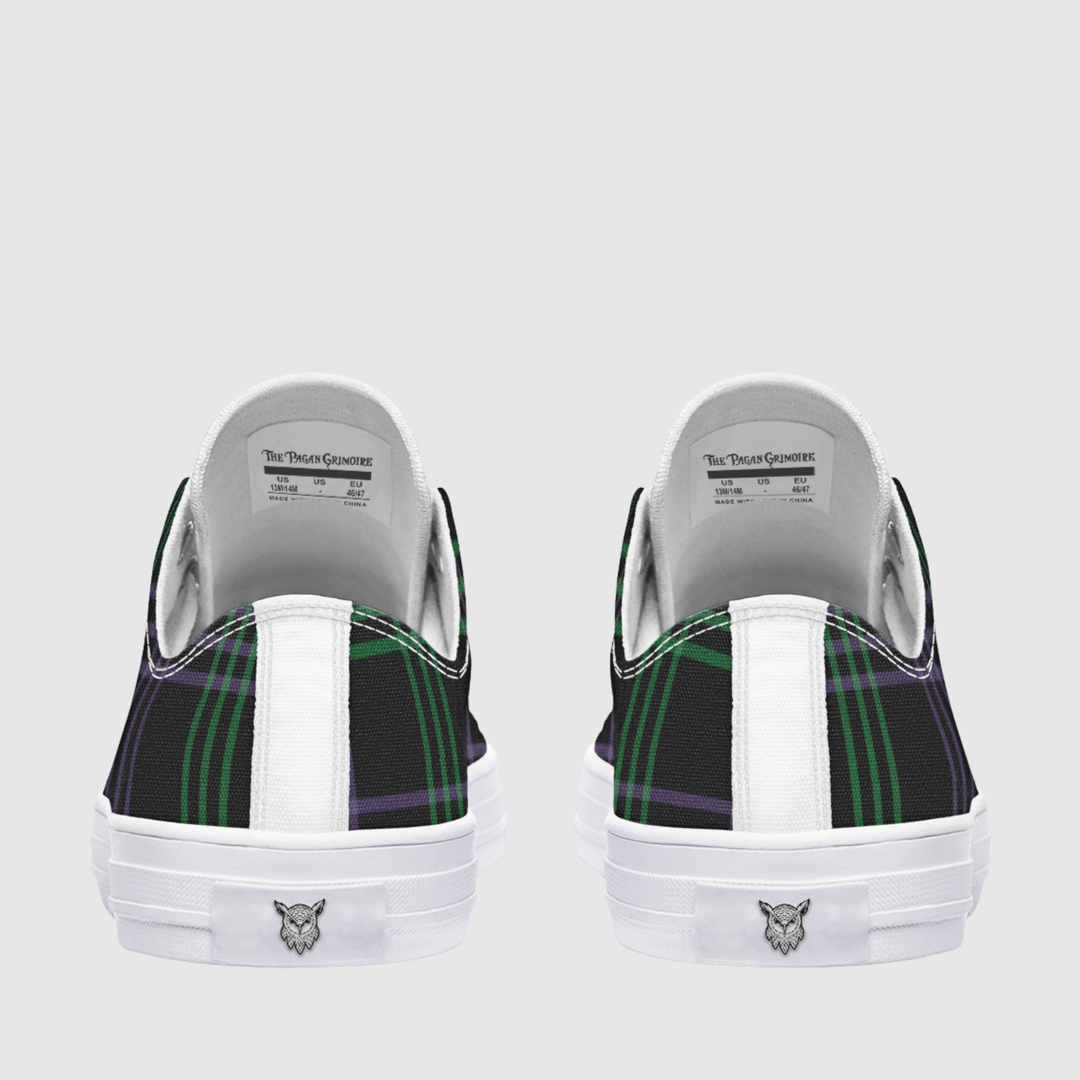 A pair of low-top sneakers shown from the back, featuring a black and green tartan plaid pattern on the sides, a white vertical stripe, and a white rubber sole with a small logo.