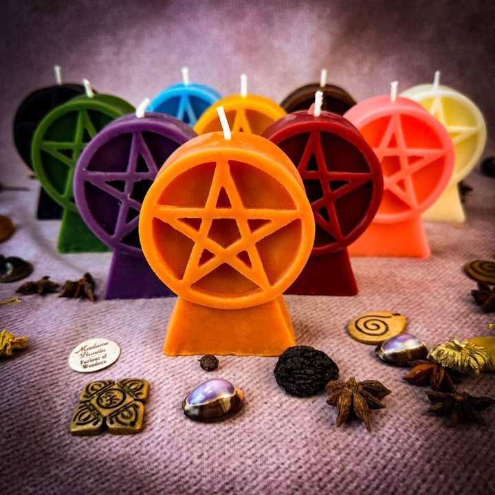 Beeswax Pentacle of Protection Spell Candle with orange pentagram cutout, surrounded by colorful candles.