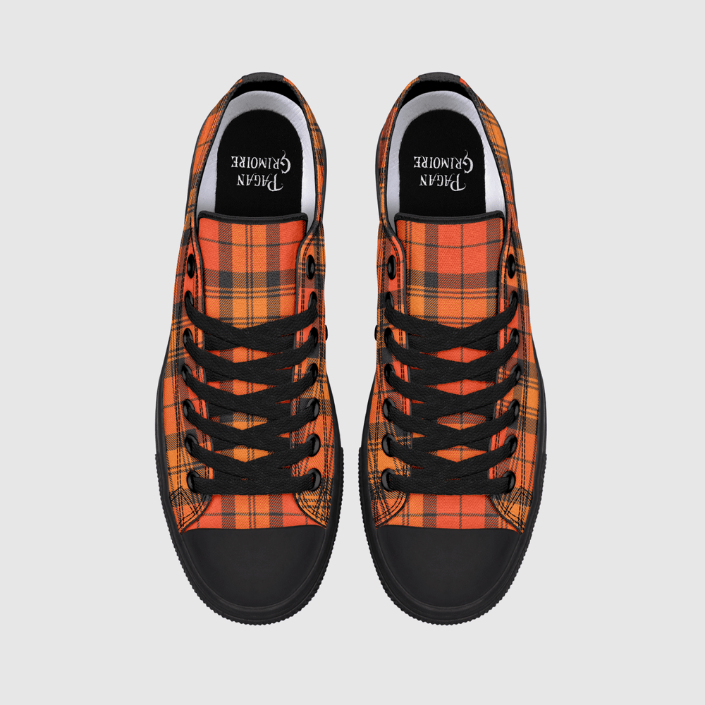 A pair of low-top canvas sneakers shown from a top-down view on a light gray background. The shoes feature a vibrant orange and red tartan plaid pattern, black laces, black rubber toe caps, and a black interior lining with the brand name printed in white.