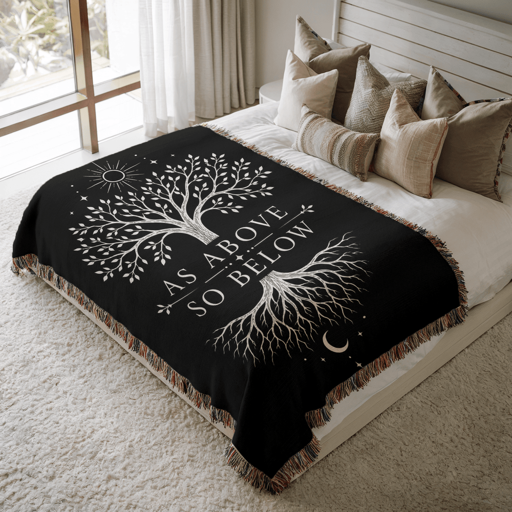 Black blanket with white tree design and As Above So Below on a bed in a bedroom.